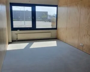Lichte, lege kantoorruimte met houten wanden en groot raam aan de Cypresbaan 3-6.