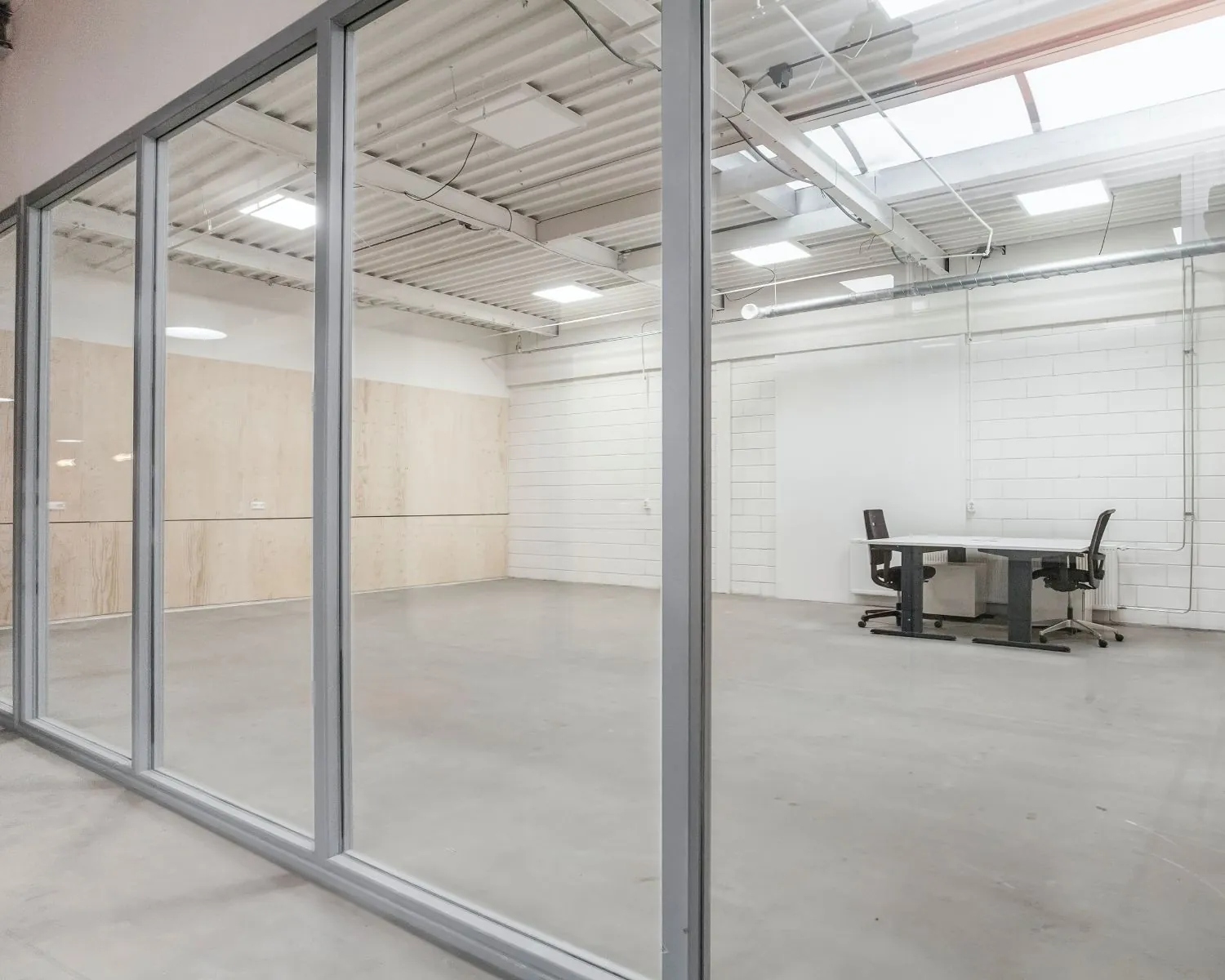 Moderne, glazen kantoorruimte te huur aan De Limiet 15 in Vianen met minimalistische inrichting en twee bureaustoelen.