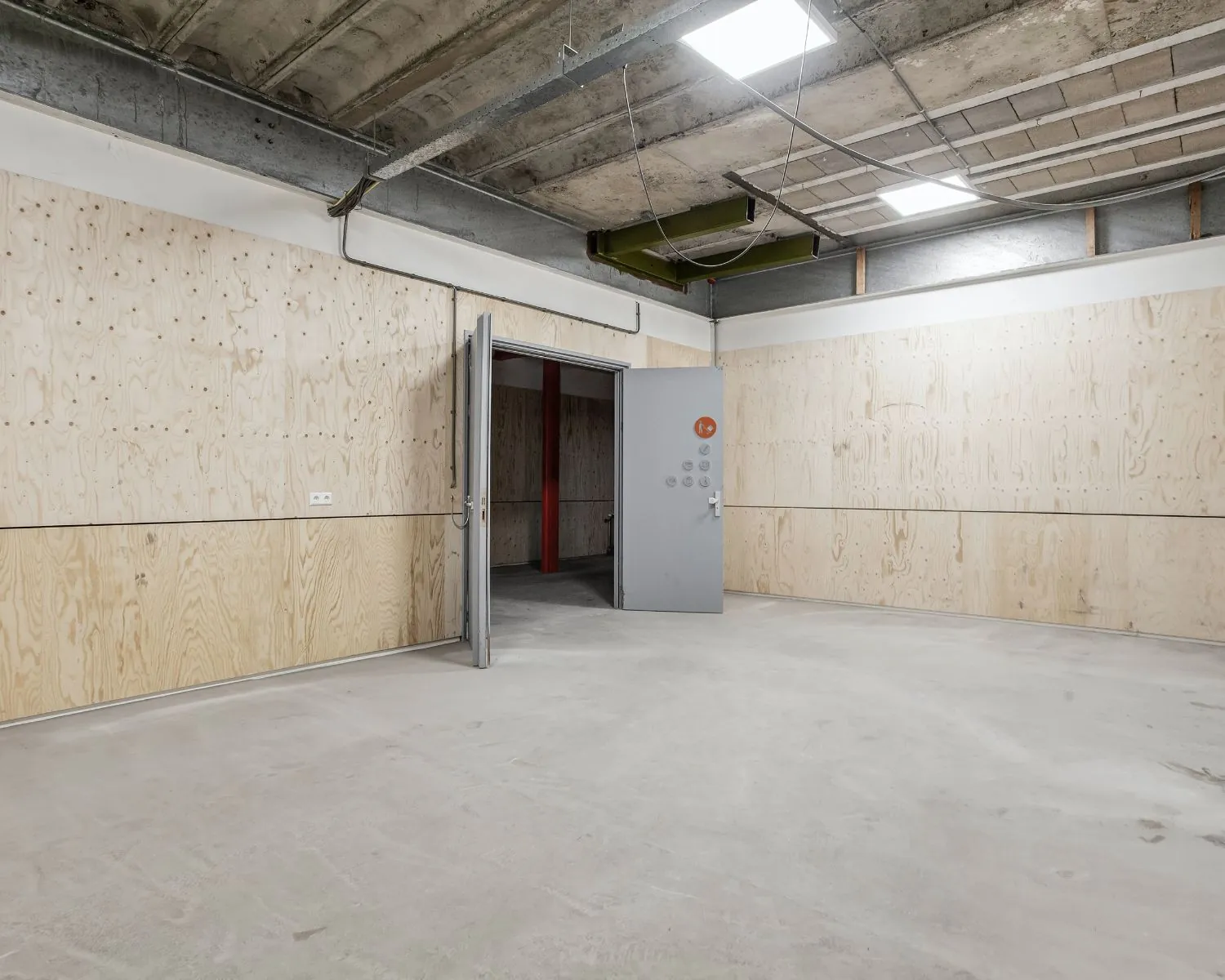 Lege kantoorruimte met betonnen vloer, houten wandbekleding en openstaande deur in De Limiet 15, Vianen.