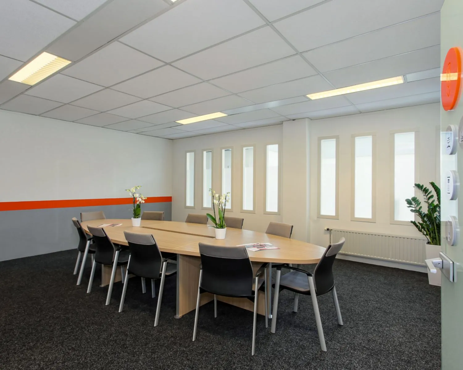 Vergaderruimte met een ovale tafel, tien stoelen en daglicht in een kantoor aan De Limiet 15 in Vianen.