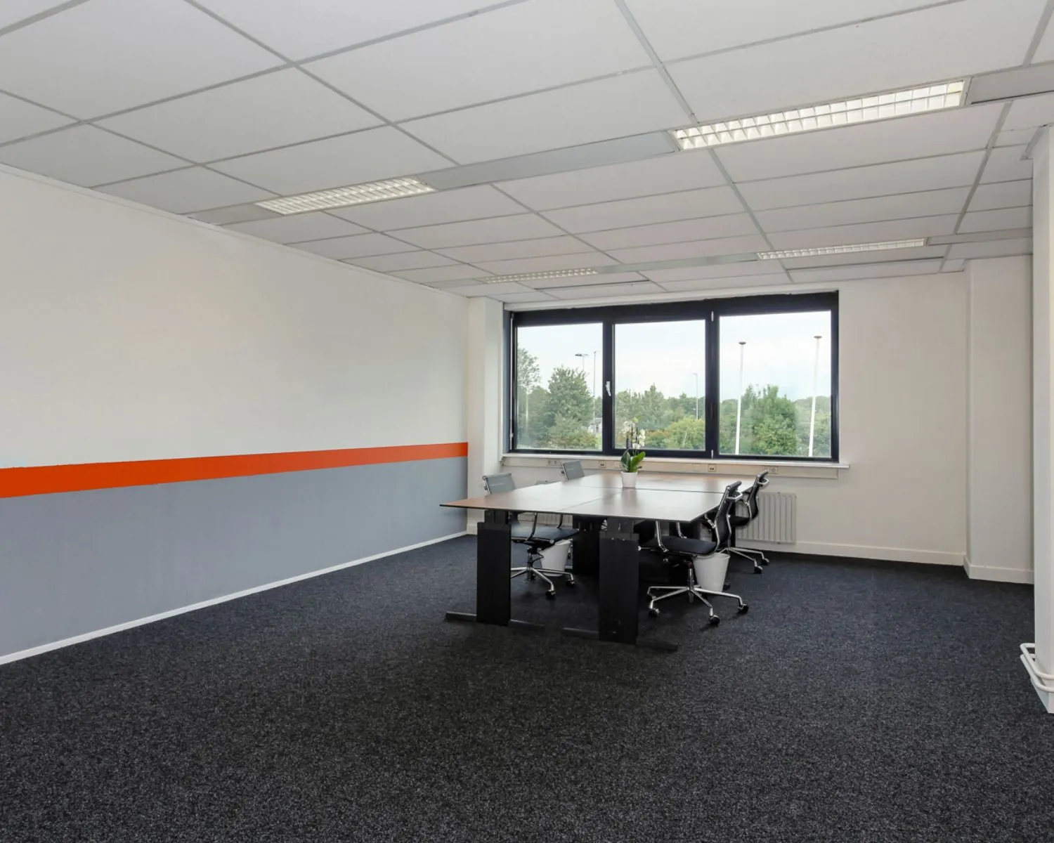 Moderne kantoorruimte te huur aan De Limiet 15 in Vianen met vergadertafel, bureaustoelen en groot raam met uitzicht op groen.