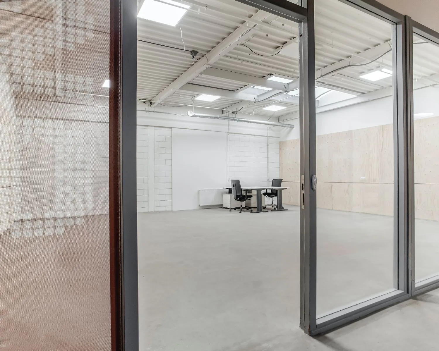 Leegstaande kantoorruimte met glazen schuifdeur aan de De Limiet 15 in Vianen, ingericht met twee bureaustoelen en een tafel.