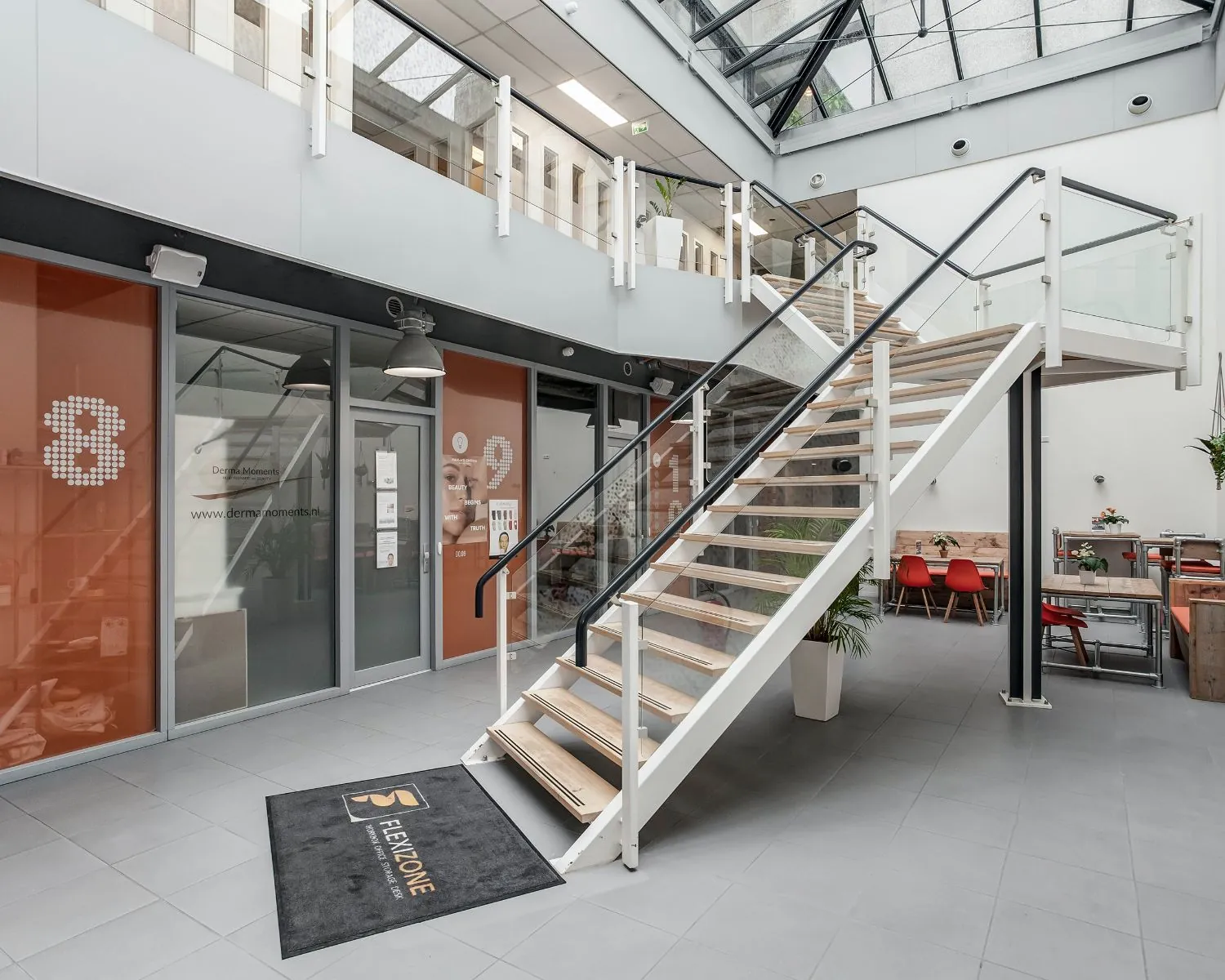 Moderne entreehal met glazen trap, zitgedeelte en kantoorruimte in bedrijfsverzamelgebouw De Limiet 15 in Vianen.