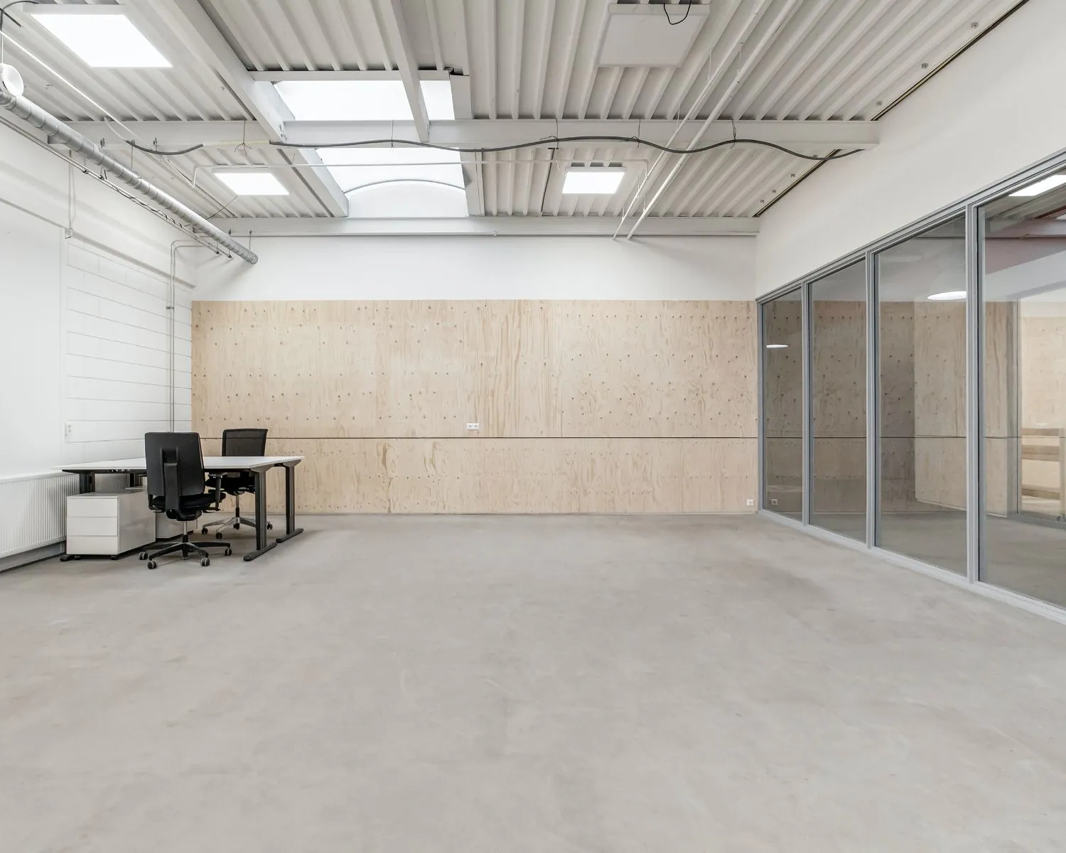 Moderne, lege kantoorruimte te huur aan De Limiet 15 in Vianen met glazen wand, houten accentmuur en twee bureaus.