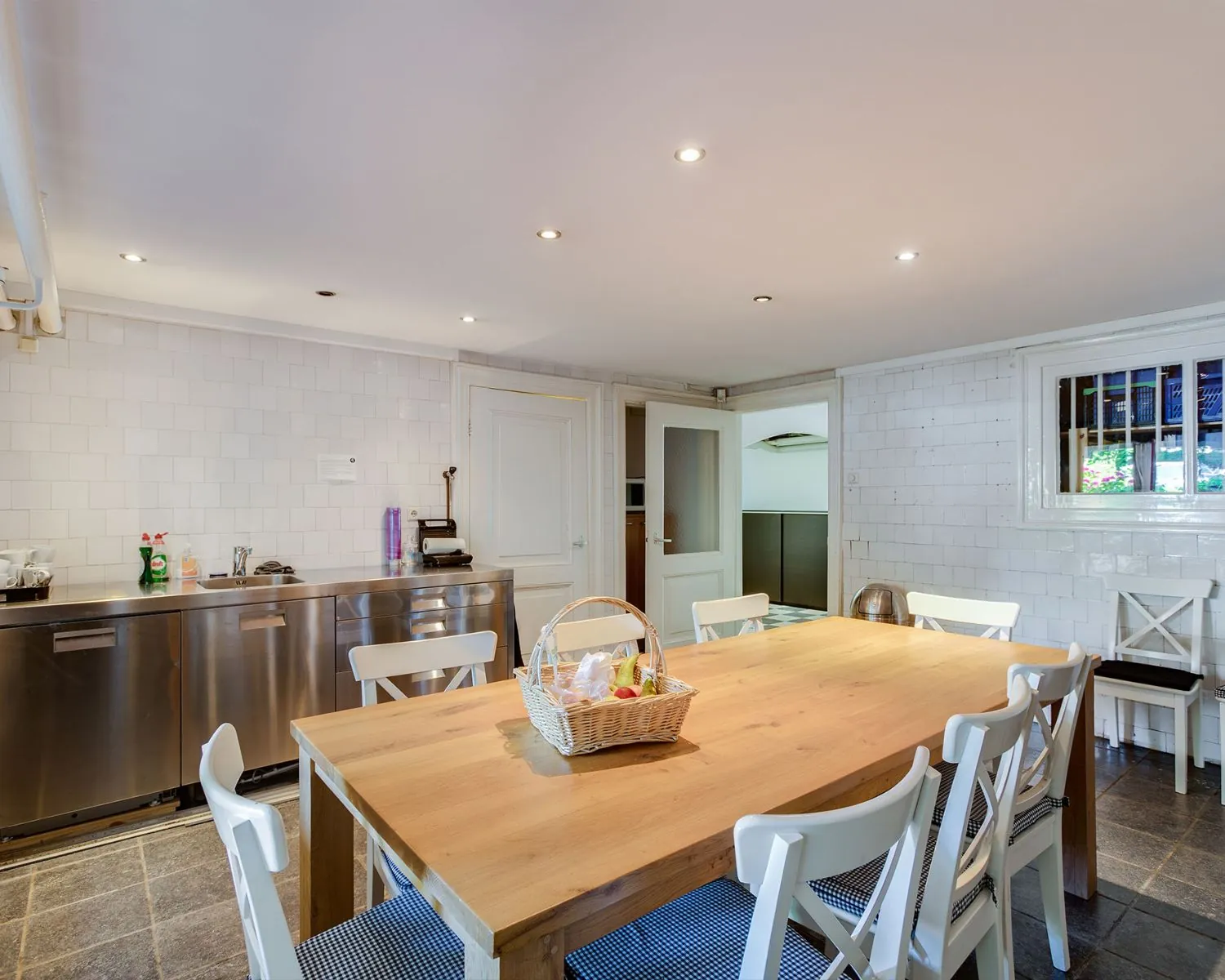 Gemeubileerde pantry met houten eettafel, witte stoelen en roestvrijstalen keukenblad in een kantoorruimte aan de Dreef 36 in Haarlem.