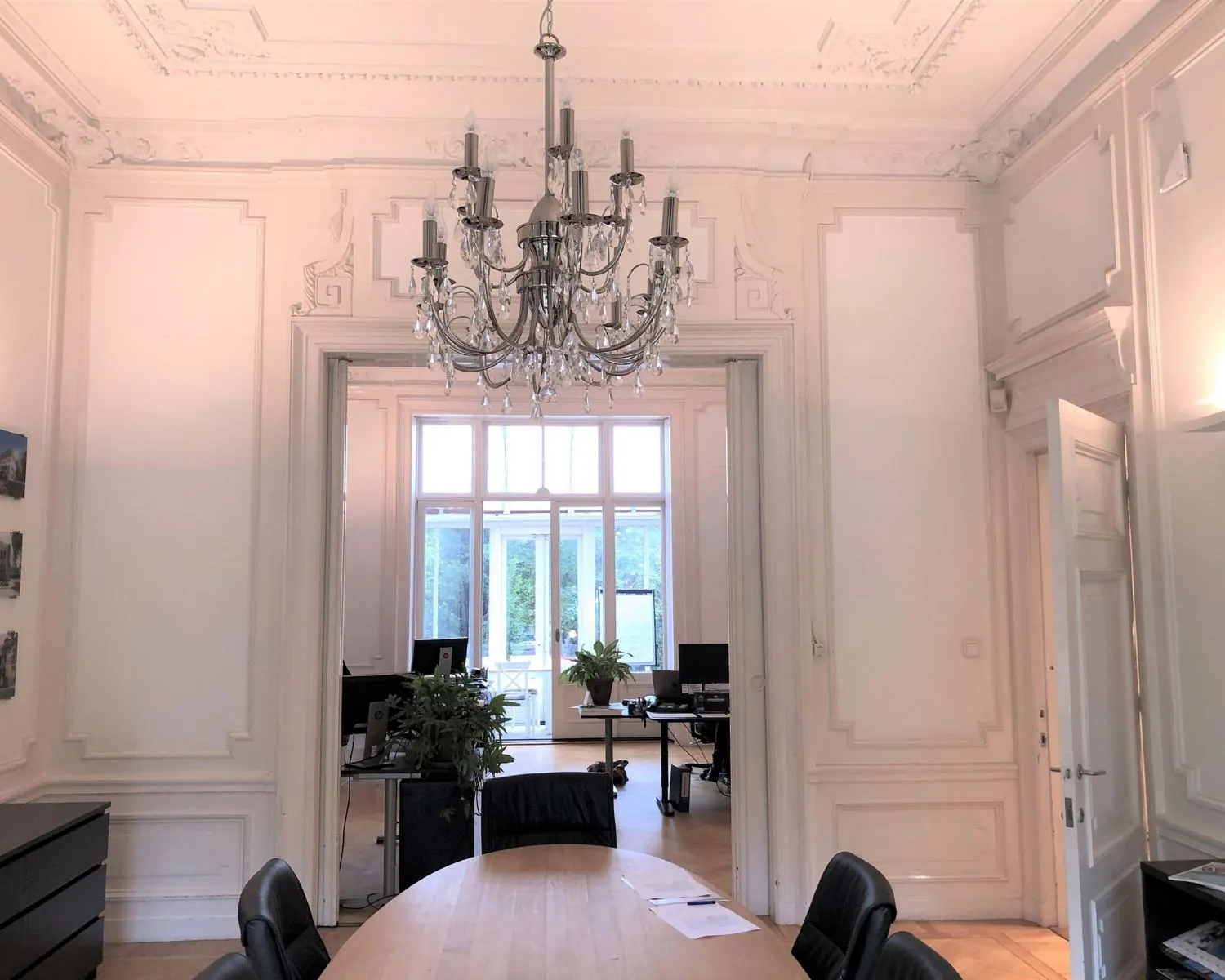 Stijlvol ingerichte kantoorruimte met hoge plafonds, klassieke wandlijsten, een kroonluchter en uitzicht op een tweede werkkamer aan de Dreef 36 in Haarlem.