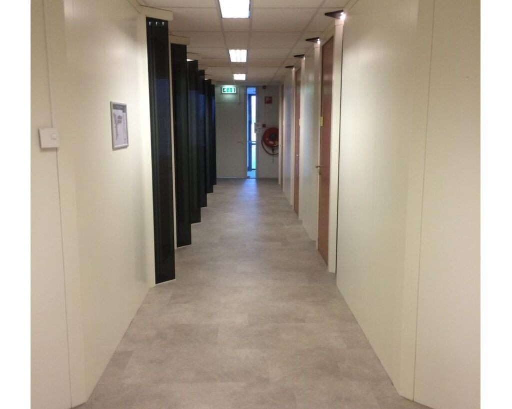 Gang in een kantoorruimte aan de Essebaan 13 met deuren aan beide zijden en een uitgang aan het einde.