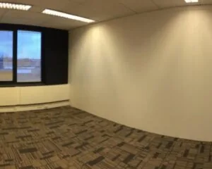 Leeg kantoor met systeemplafond, tapijttegels en een raam aan de Essebaan 13.