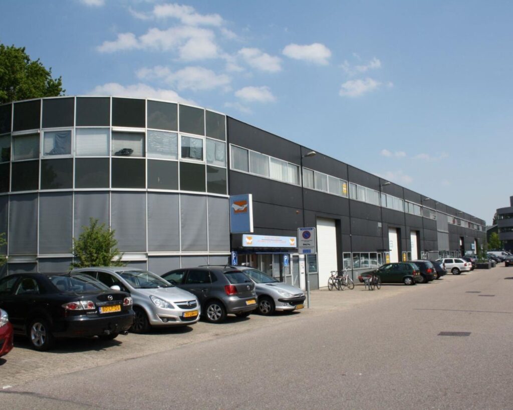 Bedrijfsverzamelgebouw met parkeerplaatsen aan de Fruitweg 16-30 in een bedrijventerrein onder een blauwe lucht.