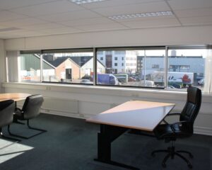 Lichte kantoorruimte met bureaus en stoelen aan de Fruitweg 16-30, met uitzicht op een bedrijventerrein.