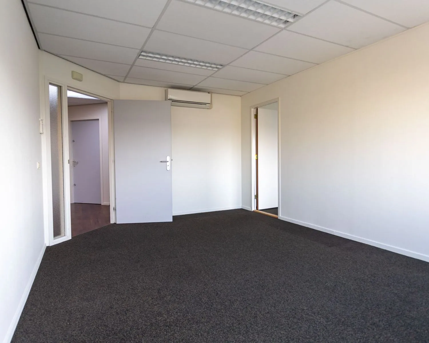 Leegstaand kantoor met grijze deuren en tapijtvloer aan de Fruitweg 16-30.