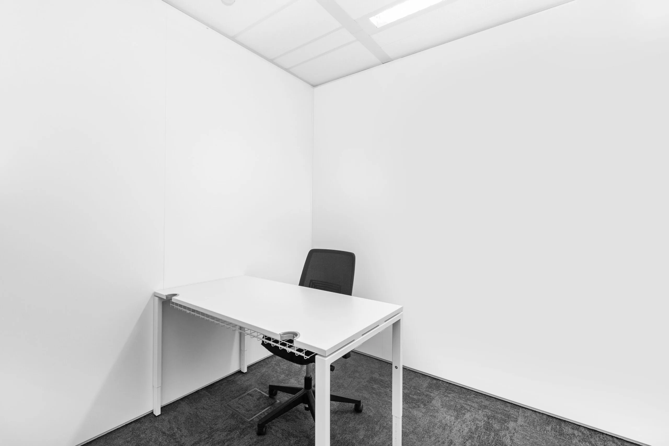 Kleine, minimalistische kantoorruimte met een wit bureau en een zwarte bureaustoel in Zwolle aan de Grote Voort 293a.