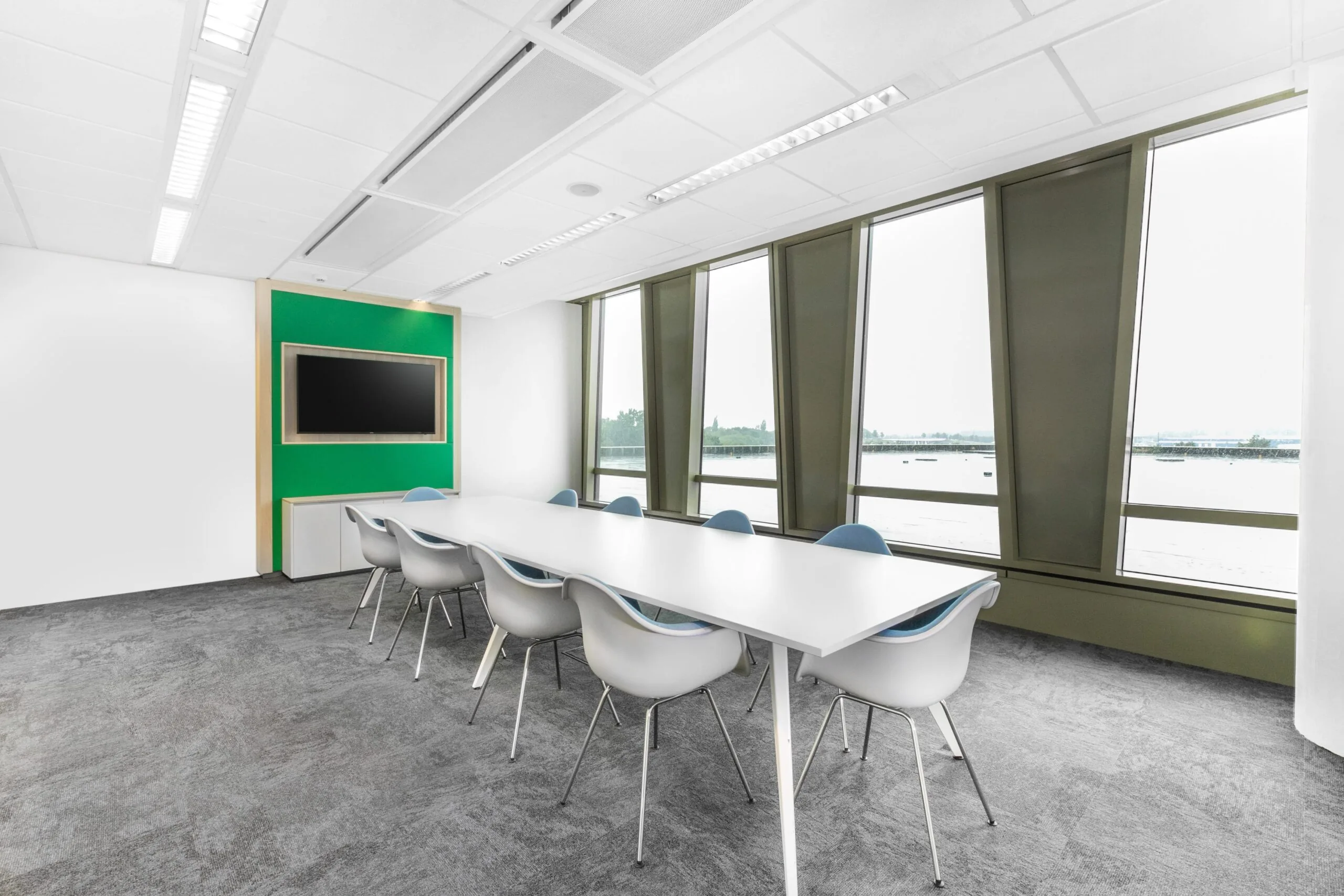 Moderne vergaderruimte met lange witte tafel, designstoelen en groot raam met uitzicht op het water in een kantoorpand aan de Grote Voort 293a in Zwolle.