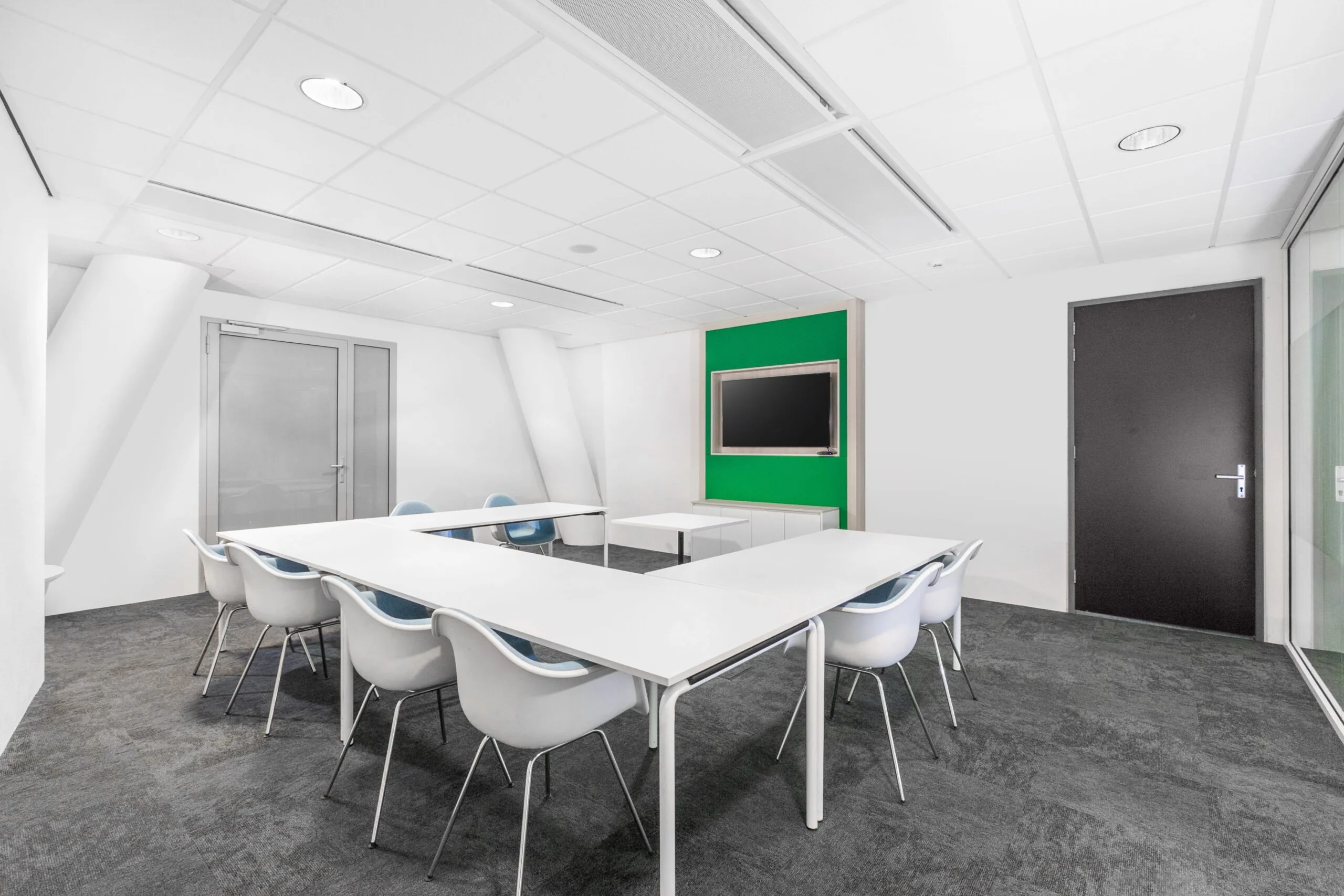 Moderne vergaderruimte met witte tafels, designstoelen en een flatscreen aan de muur in een kantoor aan de Grote Voort 293a in Zwolle.