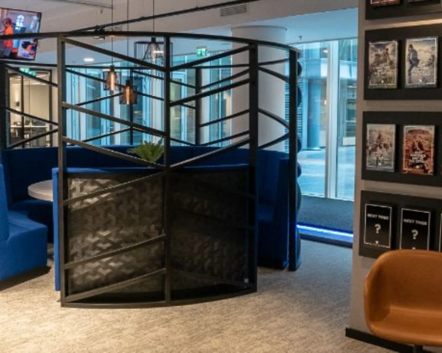 Moderne kantoorruimte met blauwe zithoeken, een metalen scheidingswand en film-posters aan de muur, gelegen aan het Gustav Mahlerplein 28 in Amsterdam.