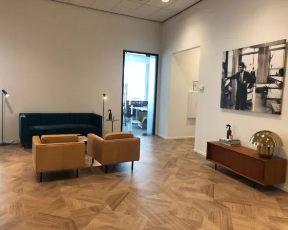 Moderne wachtruimte in kantoor aan de HJE Wenckebachweg 123 in Amsterdam met stijlvolle meubels en houten vloer.