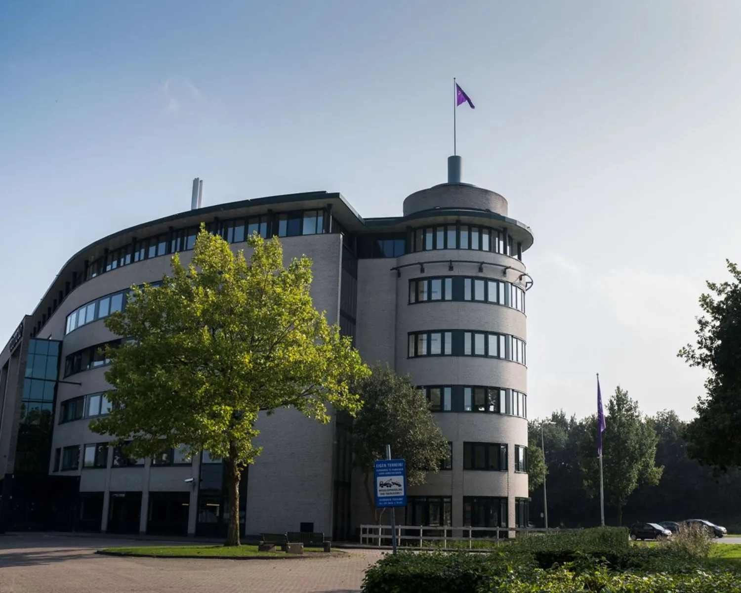Modern kantoorgebouw aan de Hanzelaan 351 in Zwolle met ronde toren en paarse vlag op het dak.