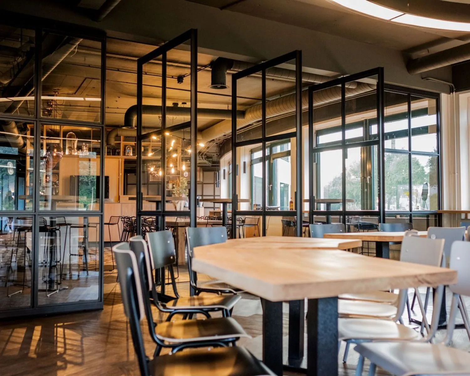 Moderne kantoorruimte met houten tafels, metalen stoelen en glazen scheidingswanden aan de Hanzelaan 351 in Zwolle.