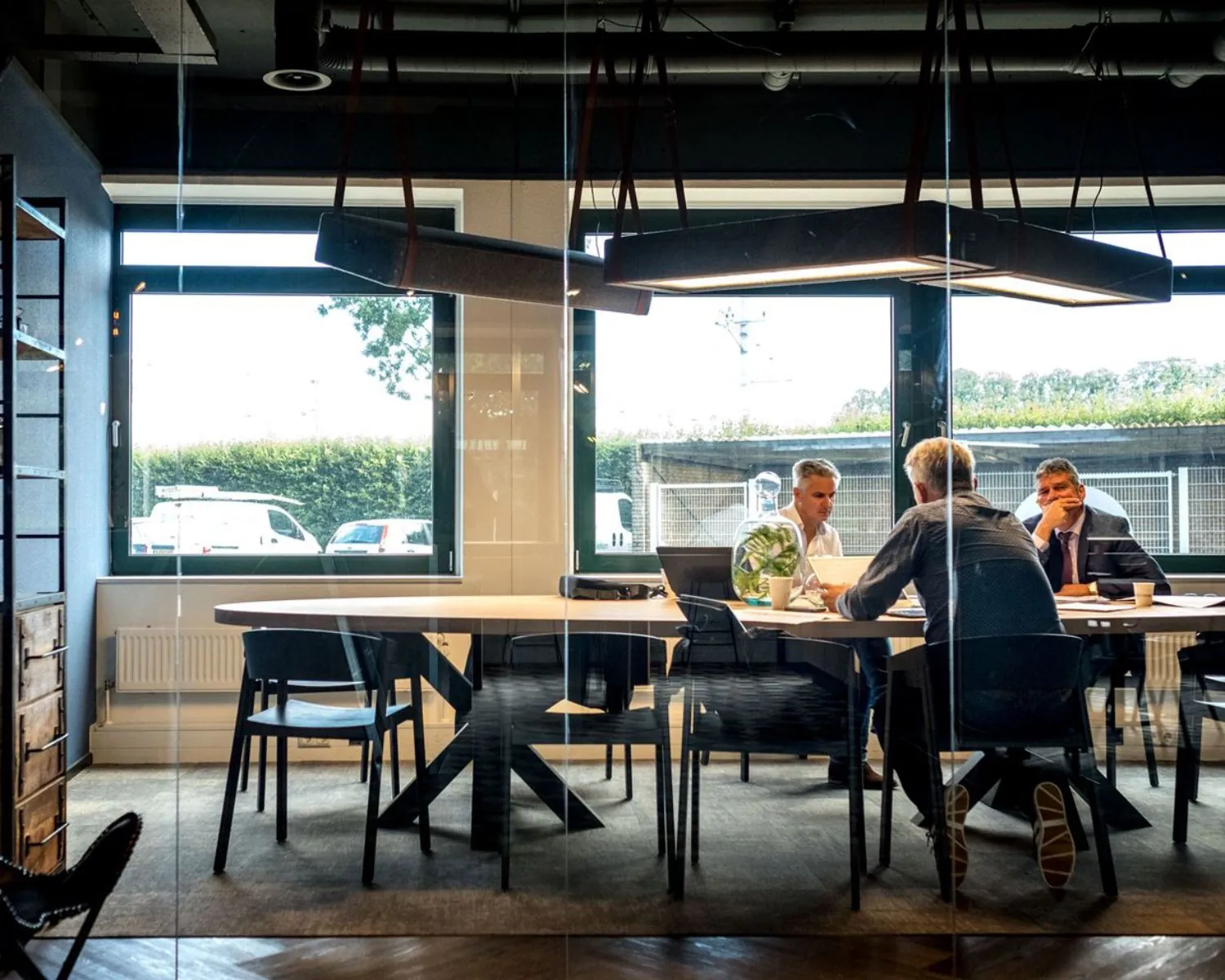 Moderne vergaderruimte aan de Hanzelaan 351 in Zwolle met drie mannen in gesprek aan een grote tafel.