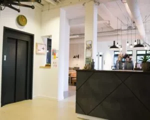 Moderne kantoorruimte met receptiebalie, zithoek en koffiecorner aan de Hogehilweg 19 in Amsterdam.