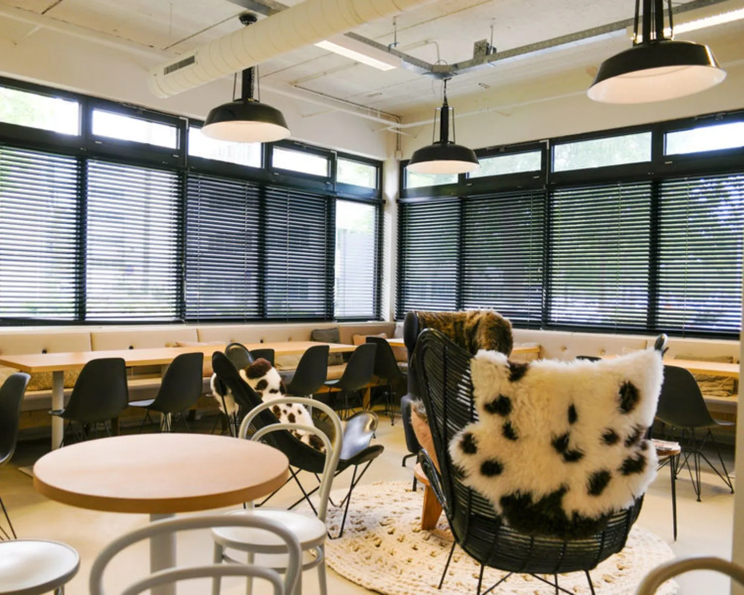 Moderne kantoorruimte aan de Hogehilweg 19 in Amsterdam met lounge- en werkplekken, ingericht met zwarte stoelen, grote ramen en sfeervolle verlichting.