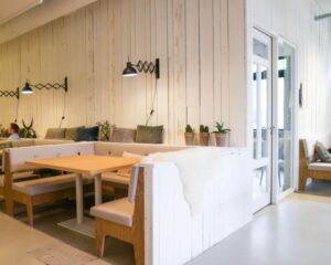 Moderne en sfeervolle zithoek met houten wanden en witte banken in een kantoorruimte aan de Hogehilweg 19 in Amsterdam.