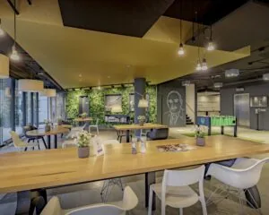 Moderne kantoorruimte aan de Hogehilweg 8 met open werkplekken, groene wand, tafelvoetbaltafel en zithoeken.