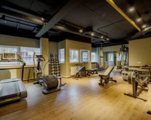 Moderne fitnessruimte in kantoorpand aan de Hogehilweg 8 met diverse trainingsapparaten en gewichten.