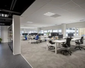 Moderne en lichte kantoorruimte met meerdere bureaus en werkplekken aan de Hogehilweg 8 in Amsterdam.