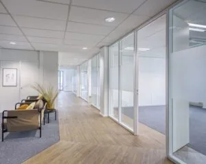 Moderne kantoorruimte aan de Hullenbergweg 4 in Amsterdam met glazen wanden, houten vloer en een zitgedeelte.