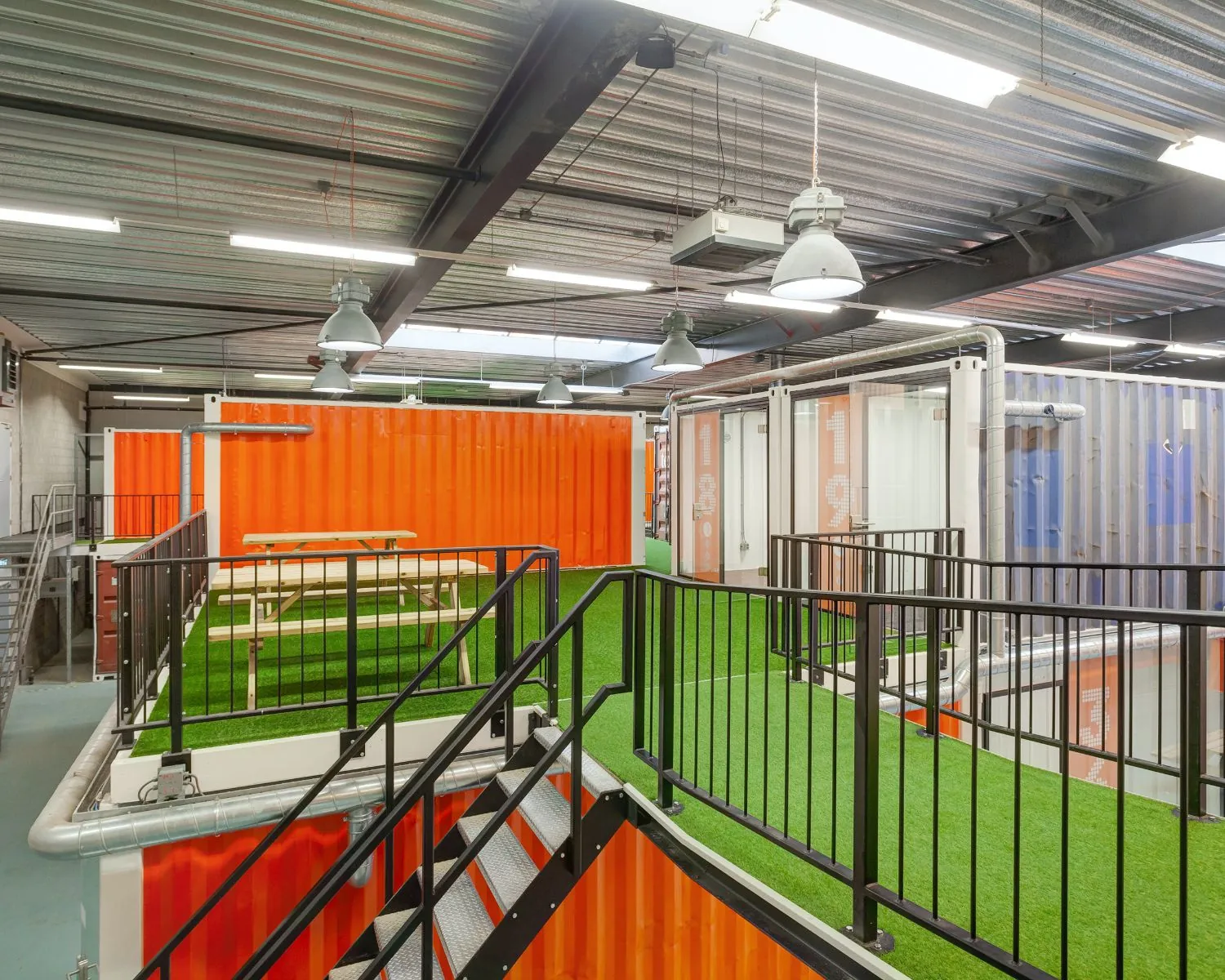 Moderne kantoorruimte in Hoofdveste 2 te Houten met felgekleurde zeecontainers, kunstgrasvloeren en industriële afwerking.