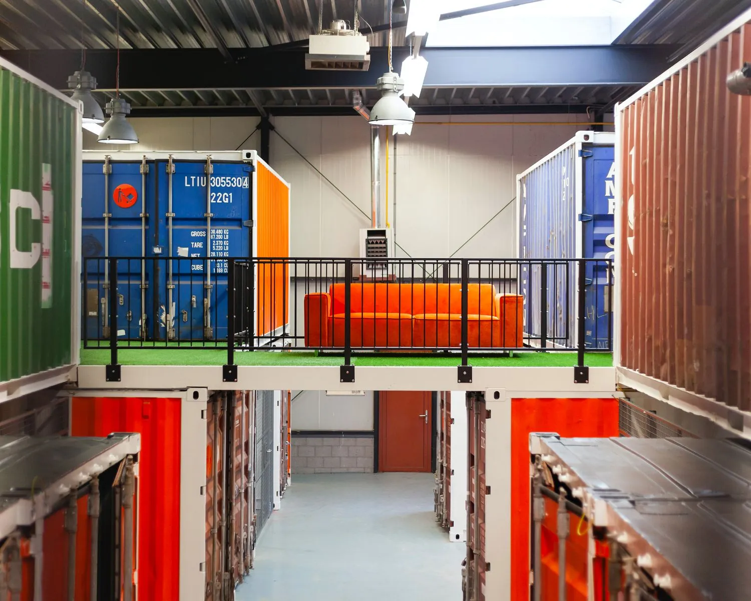 Industriële kantoorruimte in Hoofdveste 2 in Houten met kleurrijke zeecontainers en een feloranje bank op een tussenverdieping.