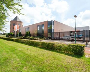 Moderne kantoorruimte te huur aan de Hoofdveste 2 in Houten met strakke gevel, parkeerplaatsen en vlaggen.