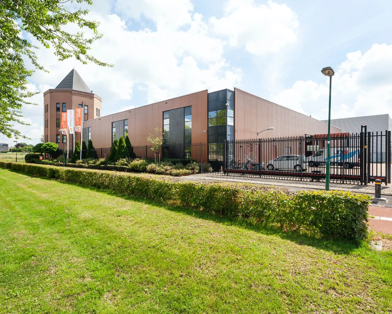 Moderne kantoorruimte te huur aan de Hoofdveste 2 in Houten met strakke gevel, parkeerplaatsen en vlaggen.