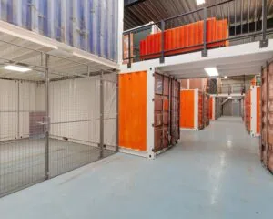 Binnenruimte met stapelbare oranje en blauwe containers ingericht als opslag- of kantoorunits in Hoofdveste 2, Houten.