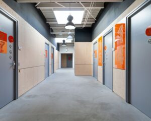 Moderne gang met kantoren in Innsbruckweg 130 in Rotterdam, met grijze deuren en oranje informatieborden.