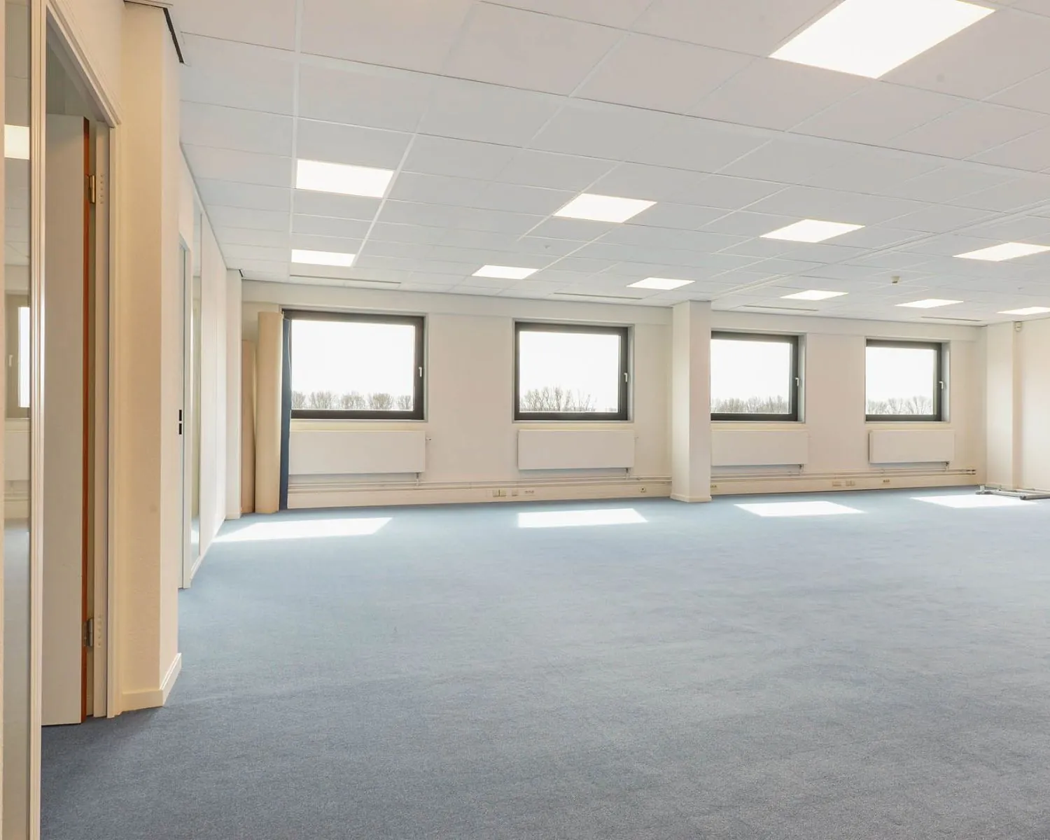 Lichte, ruime kantoorruimte met blauwe vloerbedekking aan de Joan Muyskenweg 40-146 in Amsterdam.