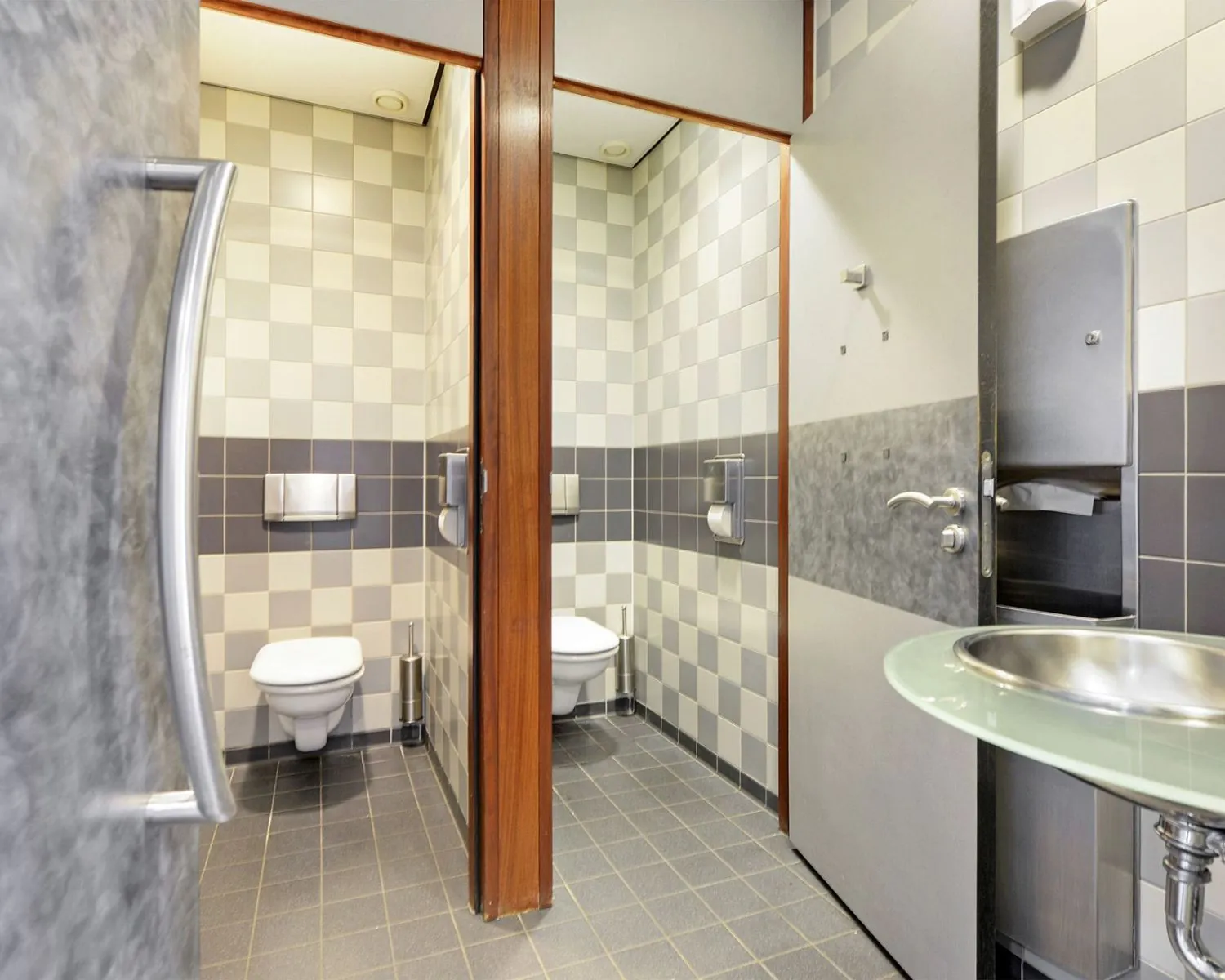 Twee moderne toiletruimtes met wandclosetten en een wastafel in een kantoorpand aan de Joan Muyskenweg in Amsterdam.