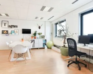 Modern ingerichte kantoorruimte met werkplekken, vergadertafel en decoratieve planten aan de Joan Muyskenweg 40 in Amsterdam.