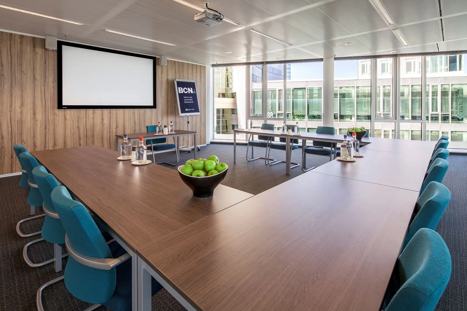 Moderne vergaderruimte in de Kennedy Tower in Eindhoven met U-opstelling, grote ramen en presentatiescherm.