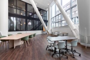 Moderne kantoorruimte in Kennedy Tower Eindhoven met grote ramen, houten vloer en diverse werkplekken.