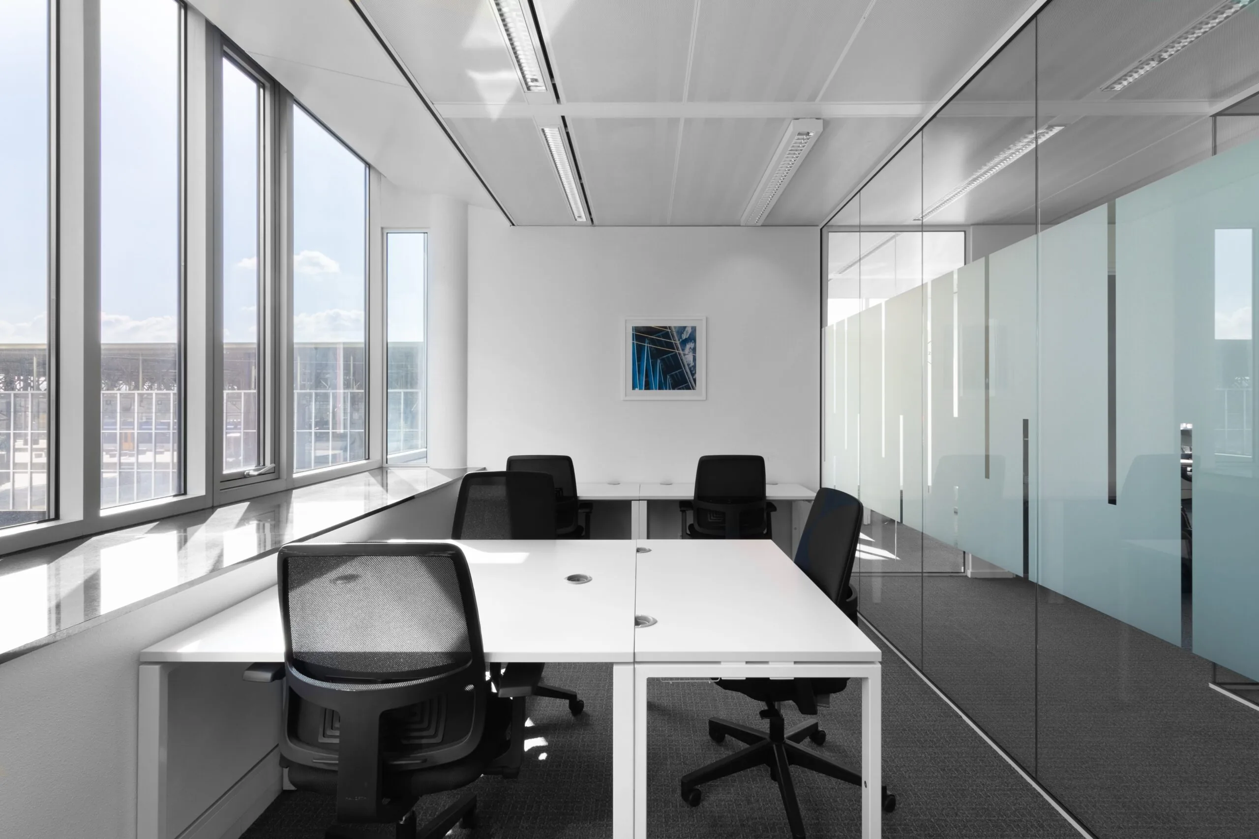 Moderne, lichte kantoorruimte met glazen wand en vier werkplekken in Kennedy Tower in Eindhoven.