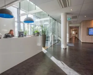 Moderne entreehal met receptiebalie en glazen wand in kantoorpand aan de Laan van Malkenschoten 40.