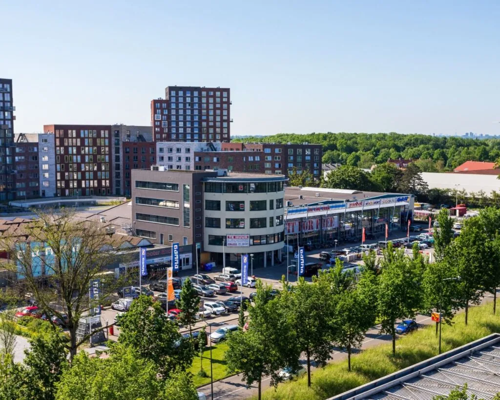 Kantoorgebouw aan de Lammenschansweg 130D in Leiden met omliggende winkels, parkeerplaatsen en woongebouwen.
