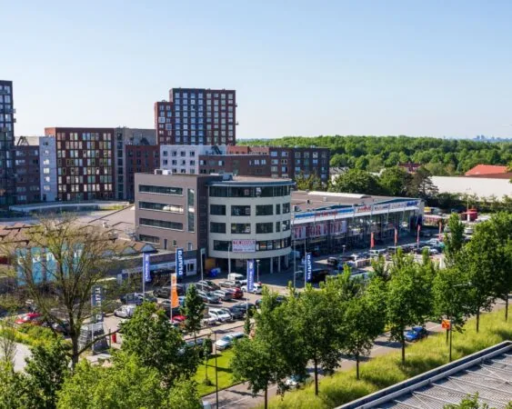 Kantoorgebouw aan de Lammenschansweg 130D in Leiden met omliggende winkels, parkeerplaatsen en woongebouwen.