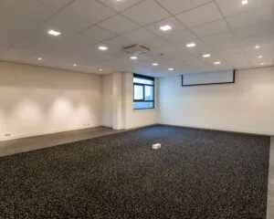 Moderne, lege kantoorruimte aan de Lammenschansweg 130D met systeemplafond, raam en projectiescherm.