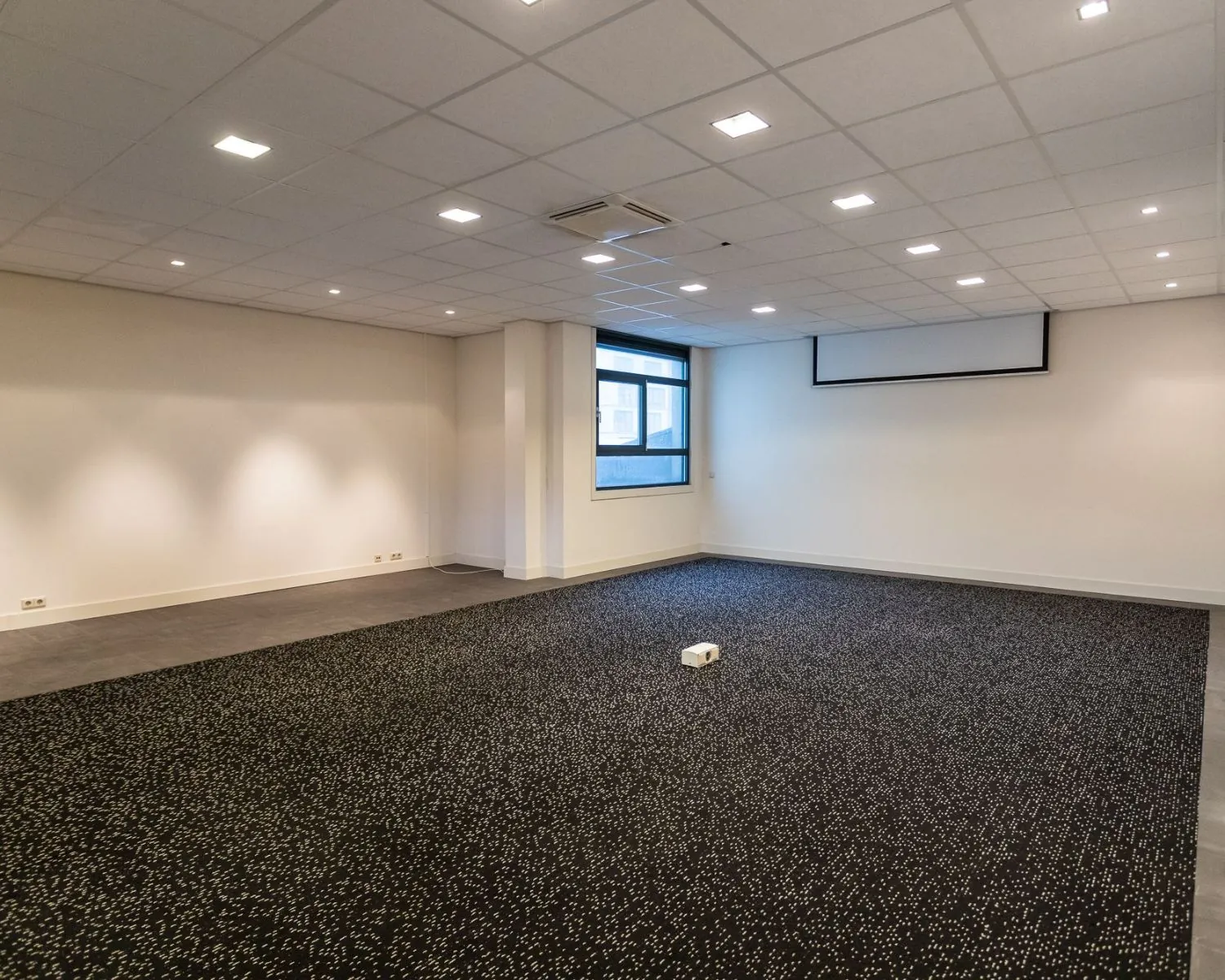 Moderne, lege kantoorruimte aan de Lammenschansweg 130D met systeemplafond, raam en projectiescherm.
