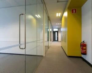 Moderne kantoorruimte aan de Lammenschansweg met glazen wanden, gele kastenwand en brandblusser in de gang.