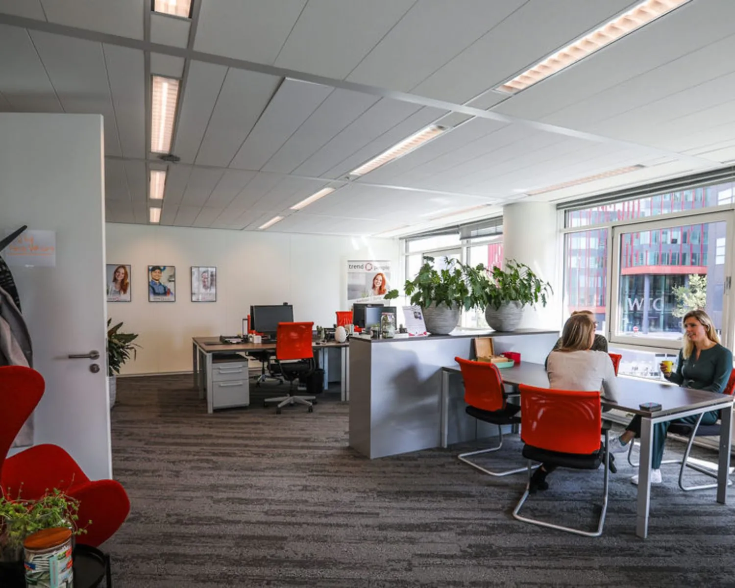 Moderne kantoorruimte aan de PJ Oudweg 41 in Almere met bureaus, rode stoelen en medewerkers in gesprek.