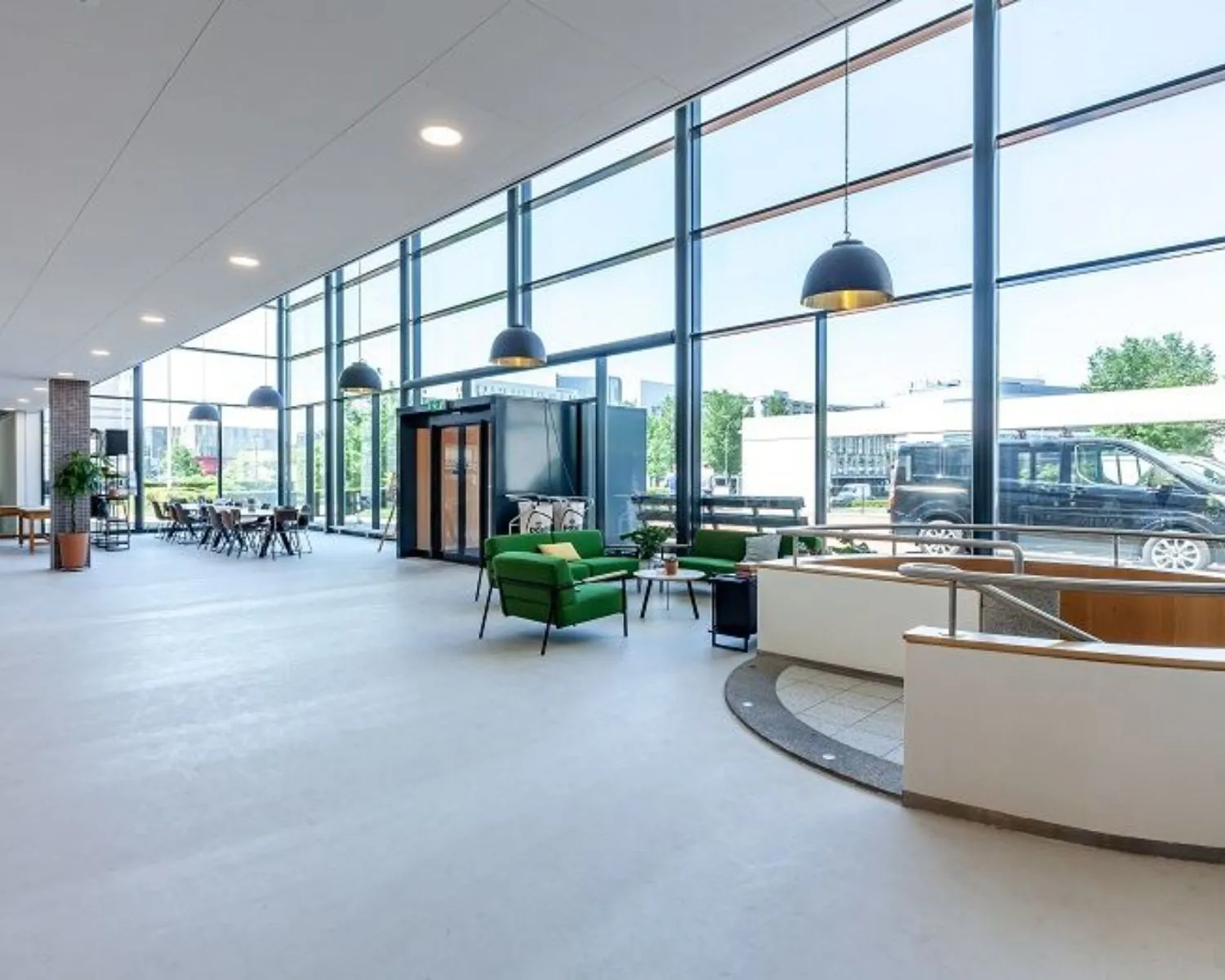 Moderne kantoorruimte aan de Polarisavenue met grote ramen, groene zitplekken en een open, lichte inrichting.